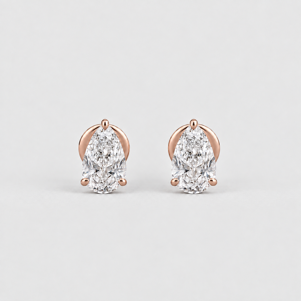 A pair of pear-cut diamond stud earrings in rose gold prong settings, displayed on a clean light gray background.