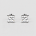 A pair of princess-cut diamond stud earrings in a silver four-prong setting, displayed on a clean light gray background.