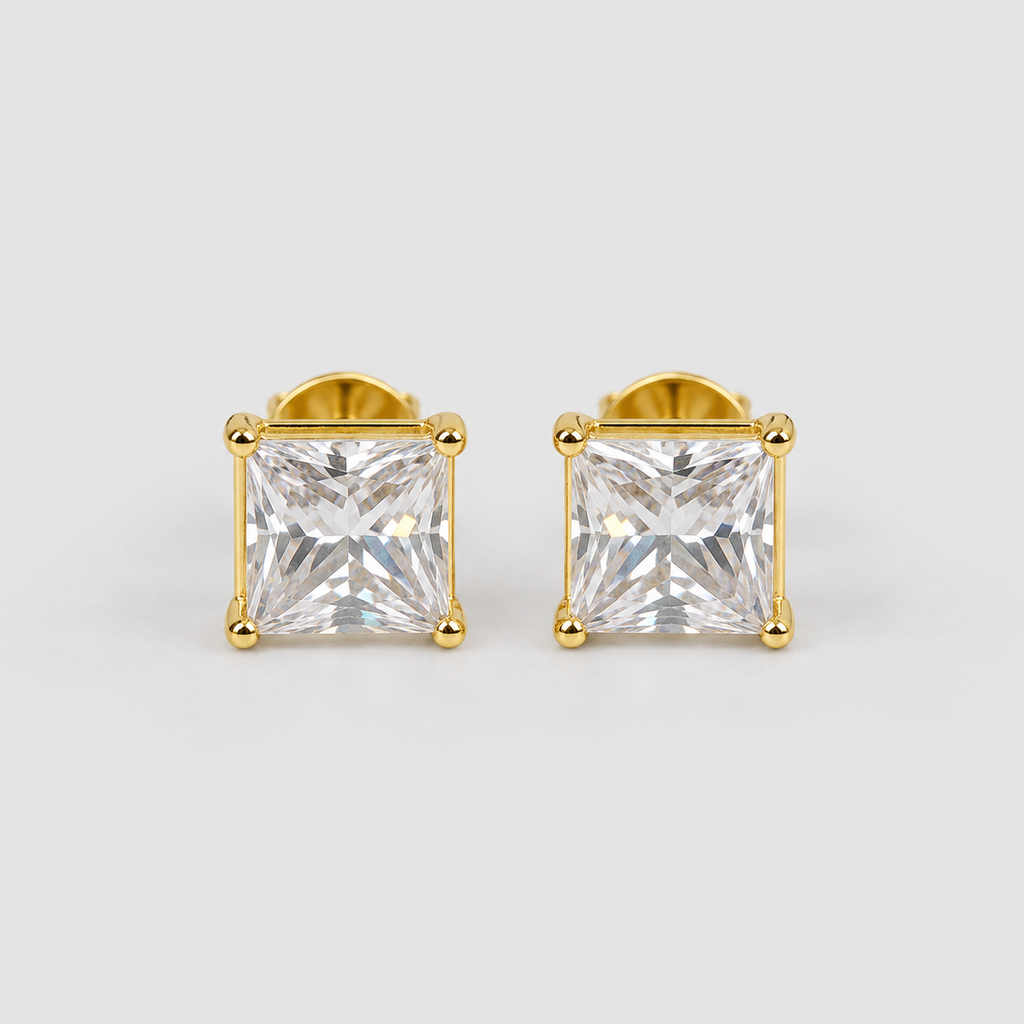 A pair of gold stud earrings featuring clear, faceted princess-cut gemstones in a four-prong setting, shown against a light gray background.