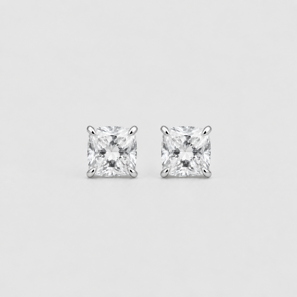 A pair of princess-cut diamond stud earrings in a silver four-prong setting, displayed on a clean light gray background.