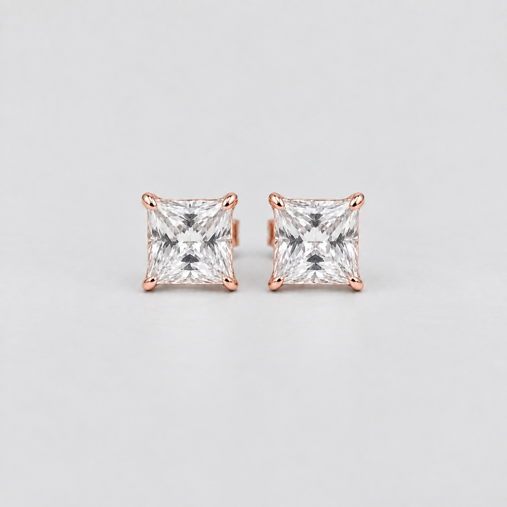 A pair of princess-cut diamond stud earrings in rose gold settings, photographed on a clean, light gray background.