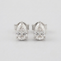 A pair of pear-cut diamond stud earrings in a silver setting, displayed on a clean, light gray background.
