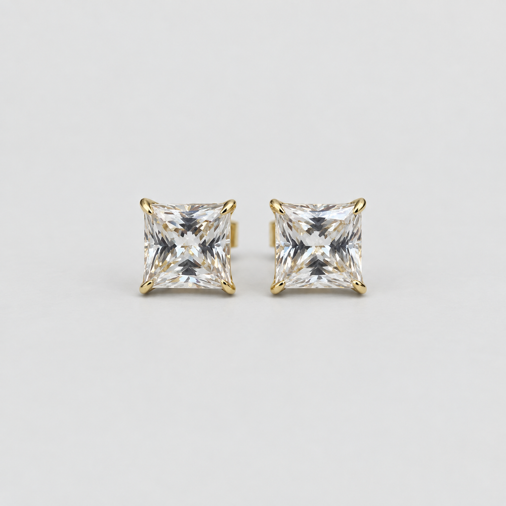 A pair of princess-cut diamond stud earrings in yellow gold four-prong settings, shown on a clean light gray background.