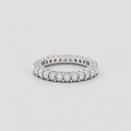 A silver diamond eternity ring with a continuous line of round-cut diamonds set in a polished silver band, photographed on a neutral light gray background.