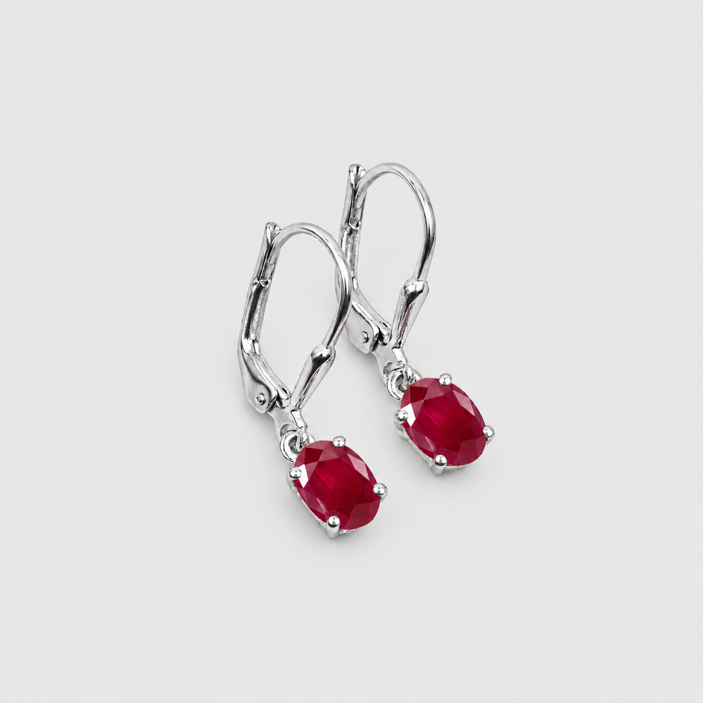 A pair of silver leverback earrings with oval-cut deep red gemstones, shown on a light gray background.