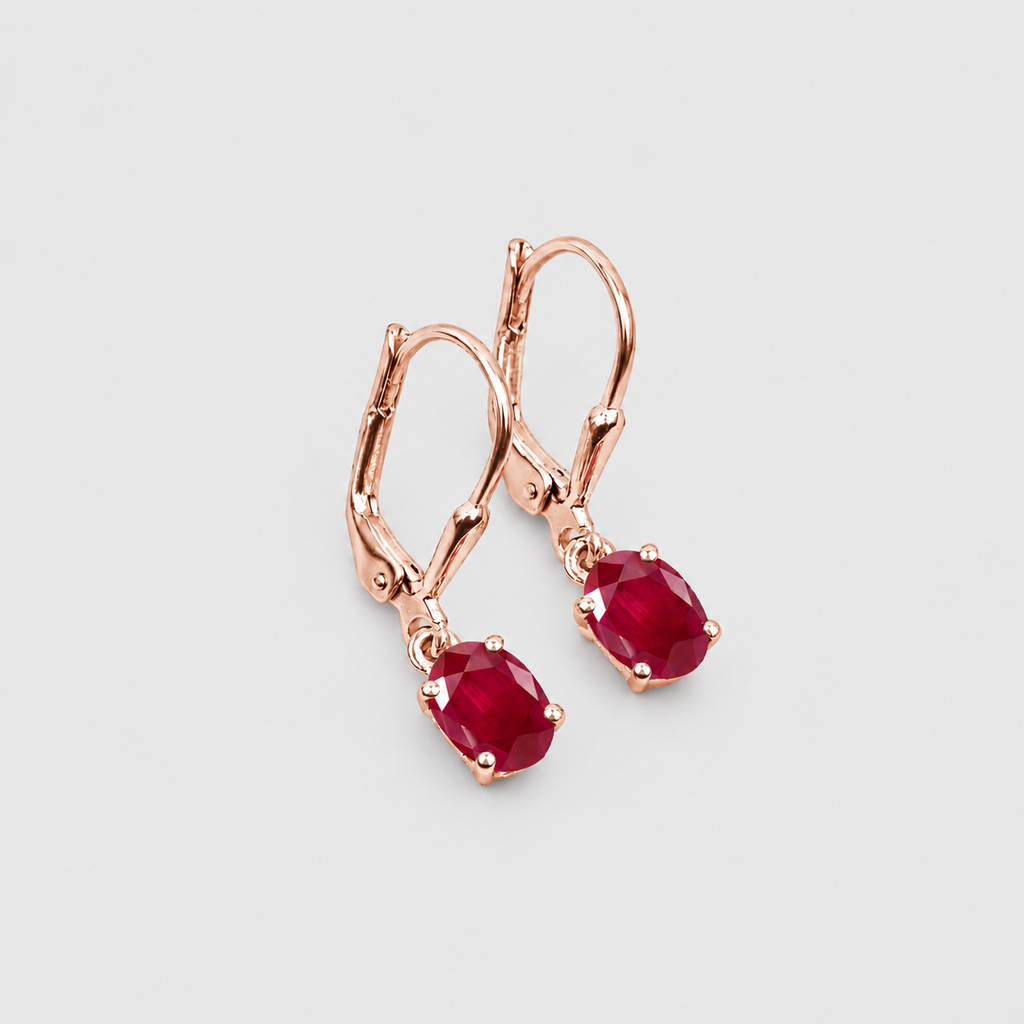 A pair of rose gold leverback earrings with oval-cut deep red gemstones, displayed on a clean light gray background.