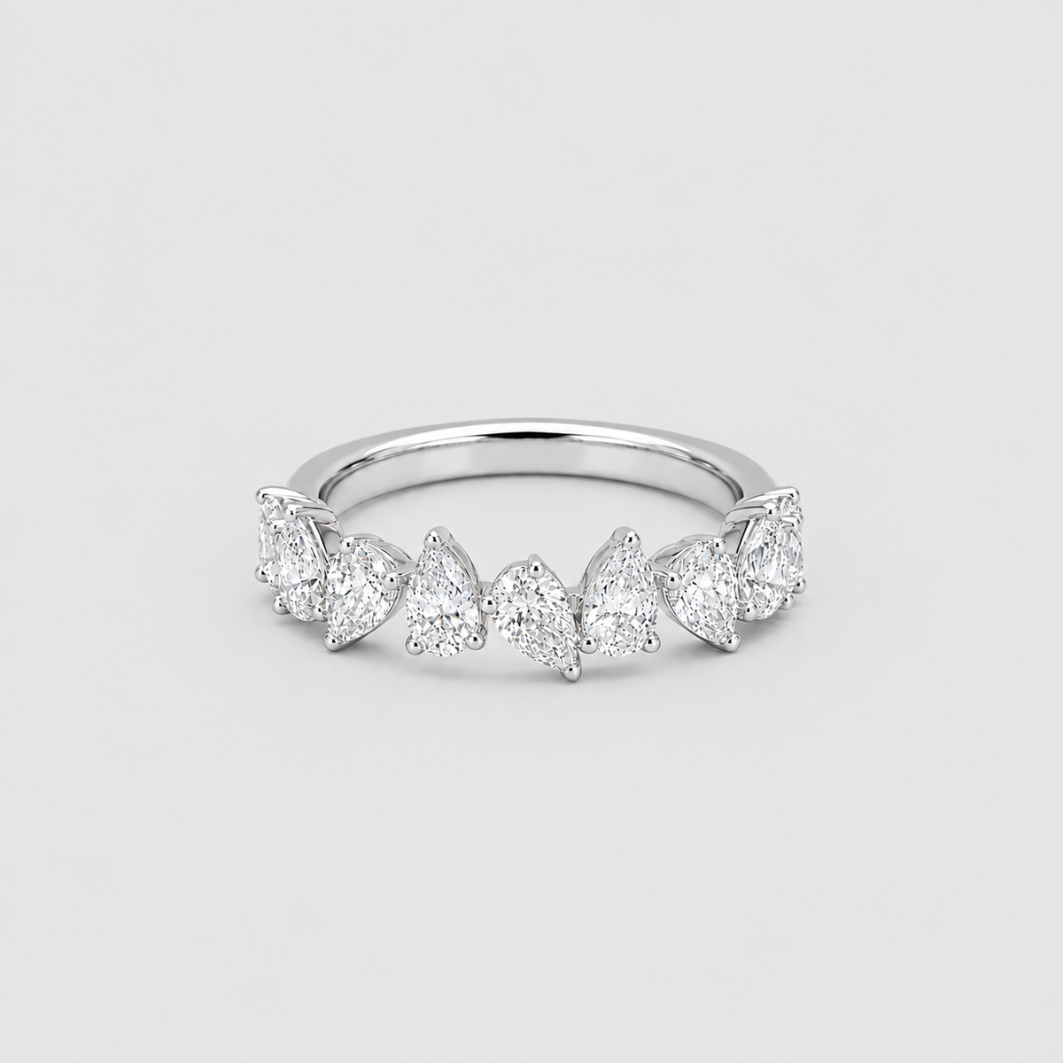 A silver band ring featuring a row of marquise-cut and round-cut clear gemstones, photographed on a light gray background.