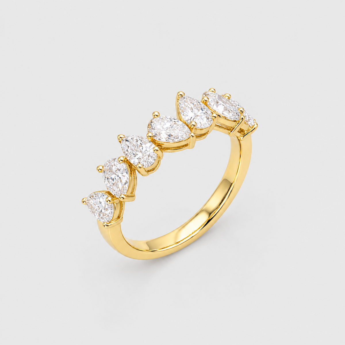 A yellow gold ring featuring a row of five pear-cut clear gemstones in a prong setting, shown on a light gray background.