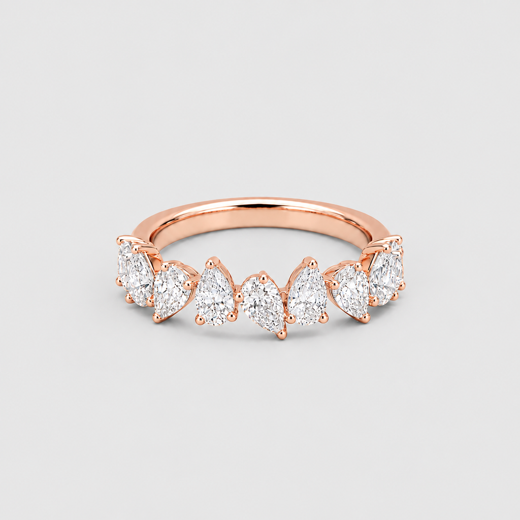A rose gold ring featuring a row of marquise-cut clear gemstones in a prong setting, shown on a neutral light gray background.