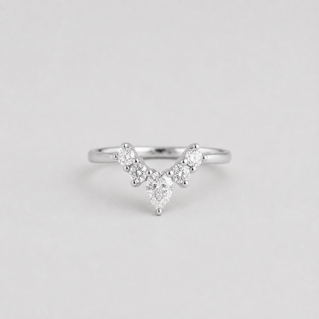 A silver V-shaped diamond ring with a pear-cut center stone and smaller round diamonds along the V, shown on a light gray background.