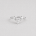 A silver V-shaped diamond ring with a pear-cut center stone and smaller round diamonds along the V, shown on a light gray background.