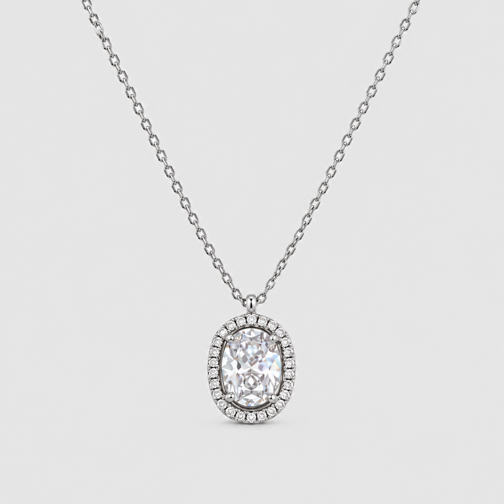 An oval halo pendant necklace featuring a brilliant-cut center stone surrounded by a halo of small pavé-set stones, suspended from a delicate silver-toned chain against a light gray background.