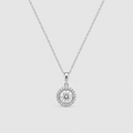 A silver-toned necklace with a box chain and a round pendant featuring a central clear gemstone surrounded by a halo of smaller stones, shown on a light gray background.