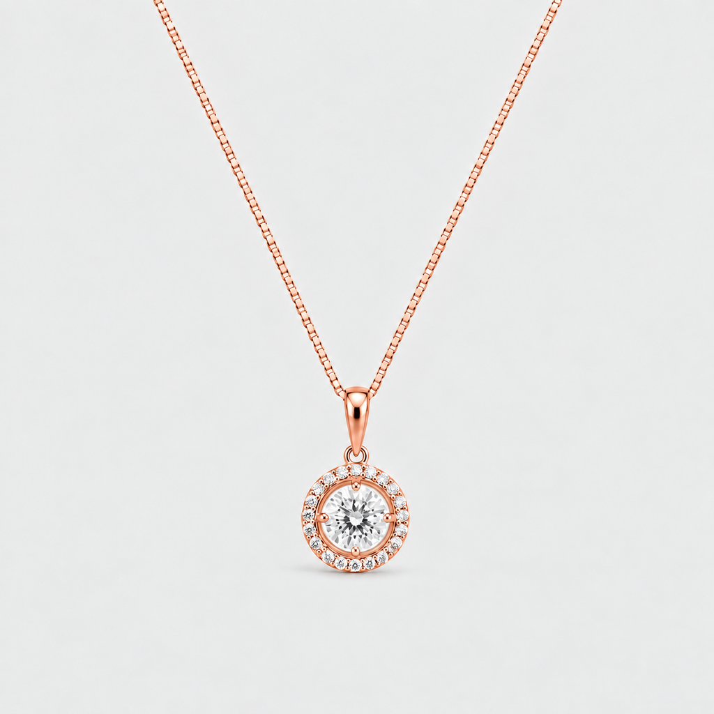 A rose gold necklace with a circular pendant featuring a central clear gemstone surrounded by a halo of small accent stones, set against a light gray background.