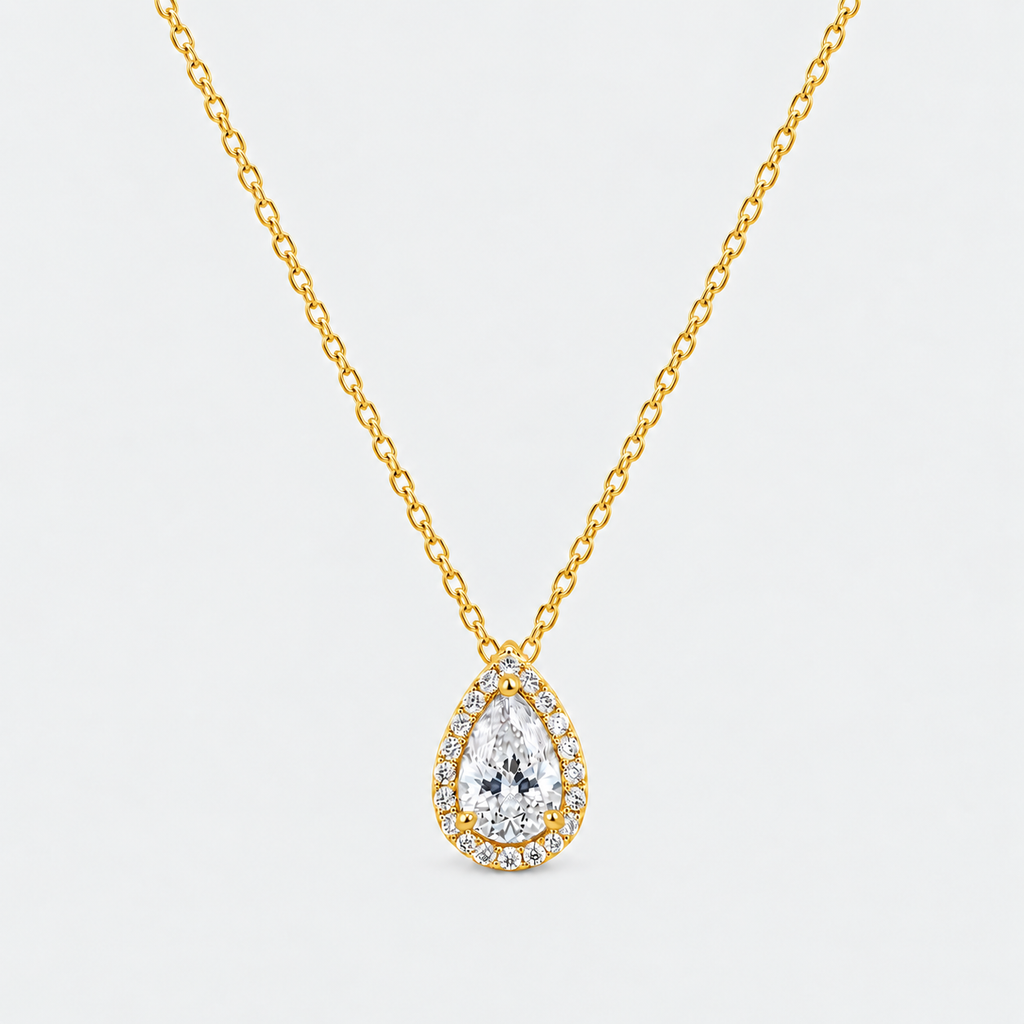 A gold chain necklace with a teardrop-shaped pendant featuring a large clear central gemstone surrounded by a halo of smaller stones, shown on a light gray background.