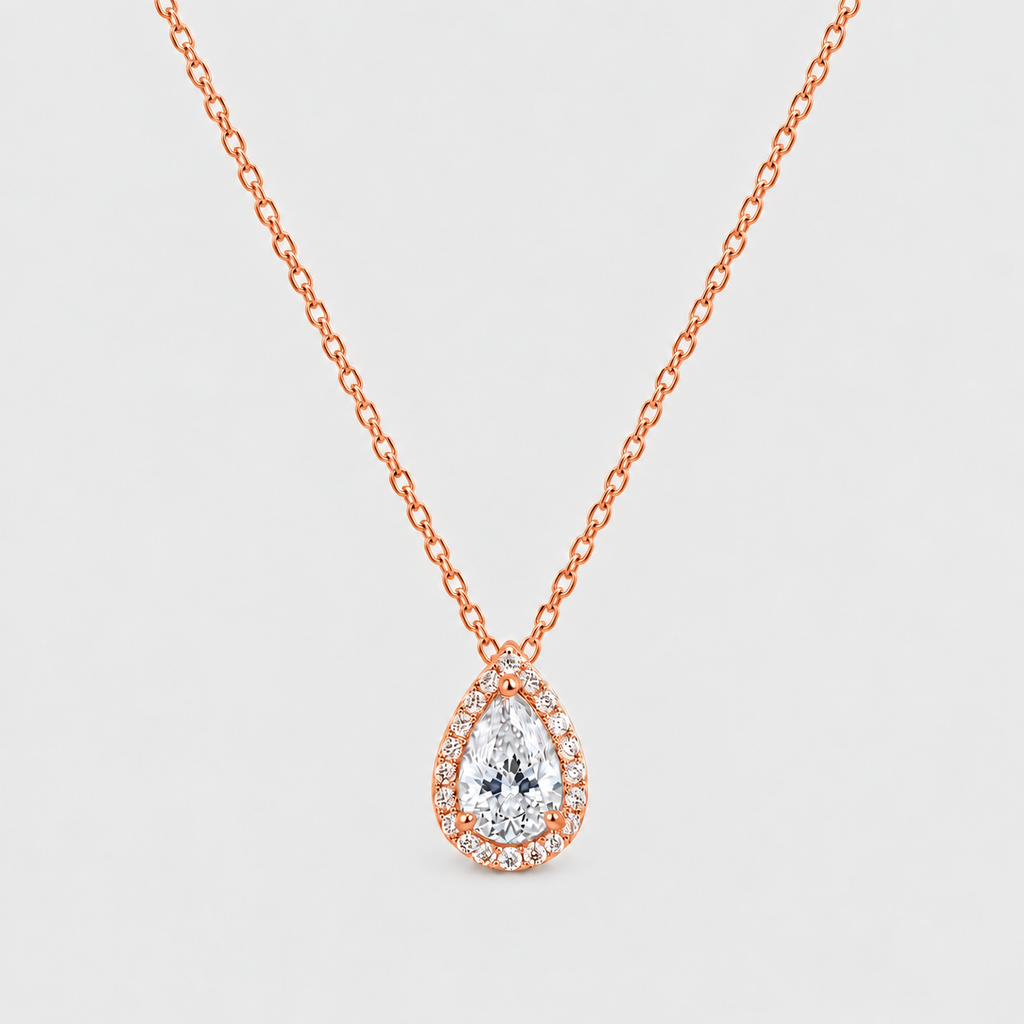 A pear-shaped diamond pendant necklace in rose gold, featuring a halo of small diamonds around the main teardrop-cut center stone, suspended from a delicate rose gold chain against a light gray background.