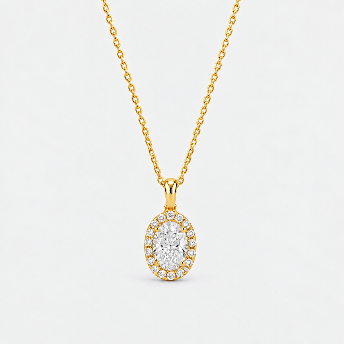 A yellow gold oval pendant necklace featuring a central round-cut diamond surrounded by a halo of smaller round diamonds, suspended from a delicate gold chain against a clean white background.