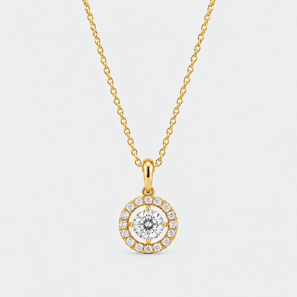 A gold chain necklace with a round pendant featuring a central clear gemstone surrounded by a halo of smaller diamonds, set against a light gray background.