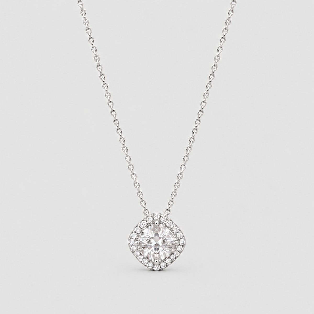 A silver-tone diamond halo necklace with a cushion-cut center stone, displayed on a light gray background.