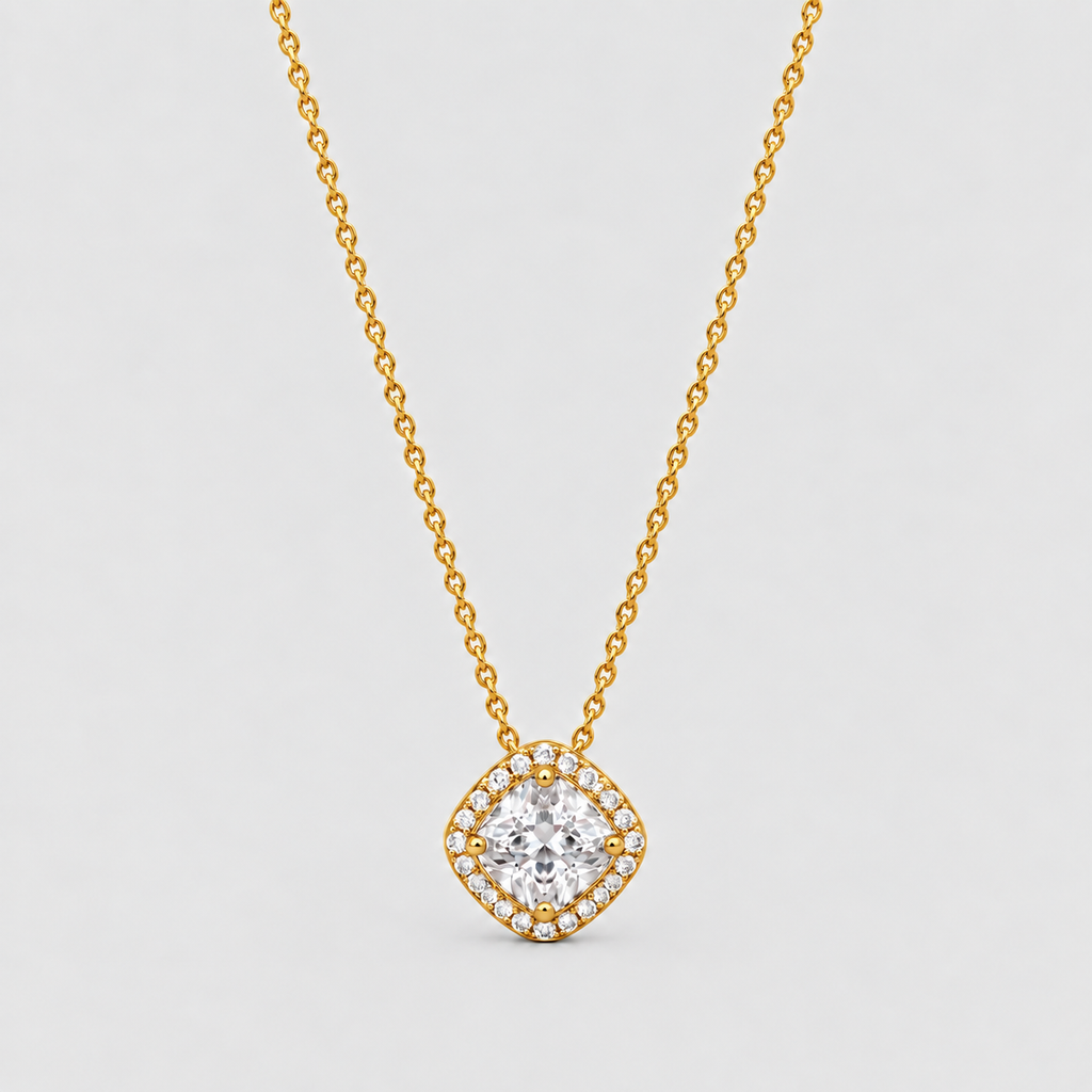 A gold chain necklace with a diamond-shaped pendant featuring a central round clear gemstone surrounded by a halo of smaller diamonds, set against a light gray background.