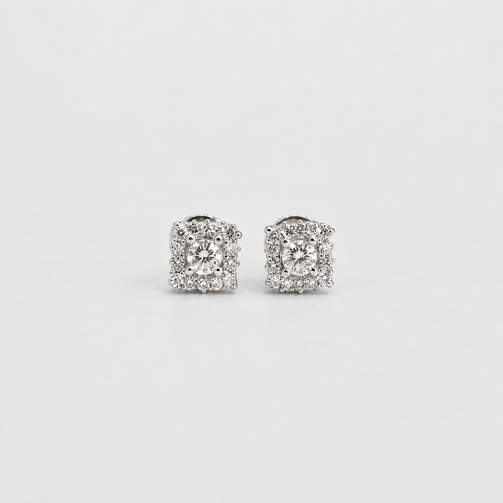 A pair of square-shaped halo stud earrings in silver-toned metal, featuring a central round clear gemstone surrounded by smaller clear stones, set against a plain light gray background.