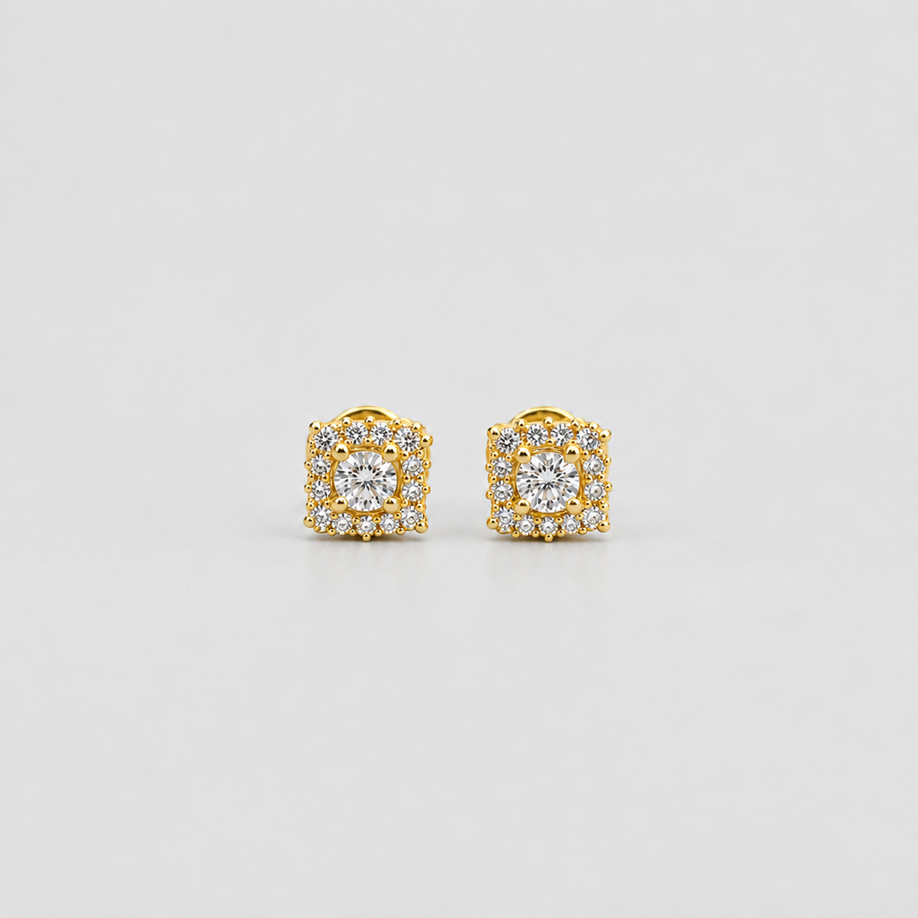 A pair of yellow gold square stud earrings featuring a central round clear gemstone surrounded by a halo of smaller clear stones, set against a plain light gray background.