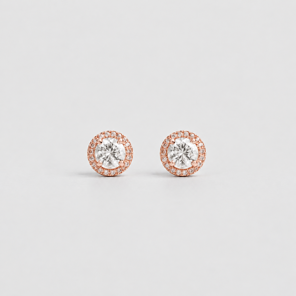 A pair of round stud earrings with a central clear gemstone surrounded by a halo of small rose gold and white stones, set against a plain light gray background.