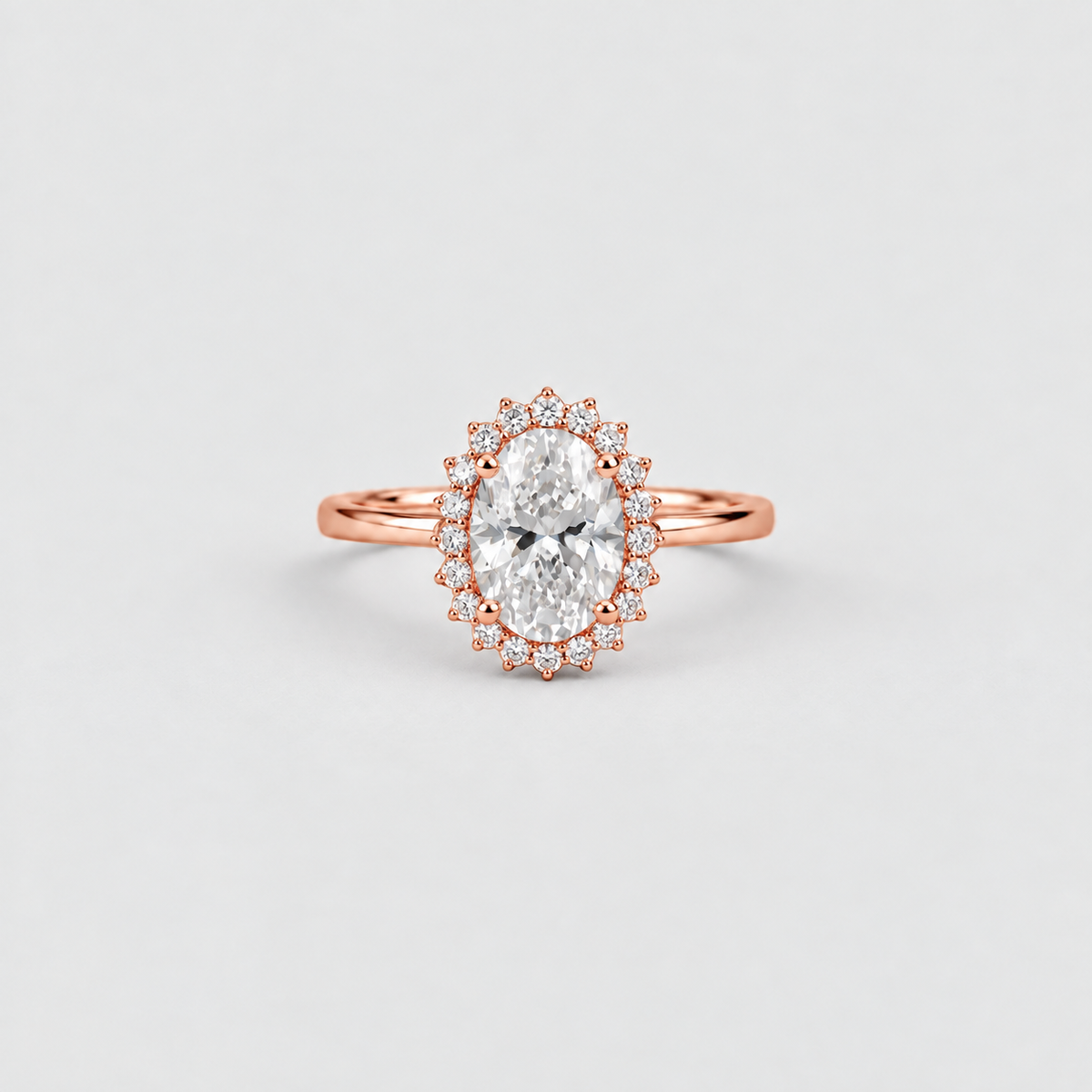 An oval-cut diamond engagement ring with a rose gold halo and a slim rose gold band, centered on a light gray background.
