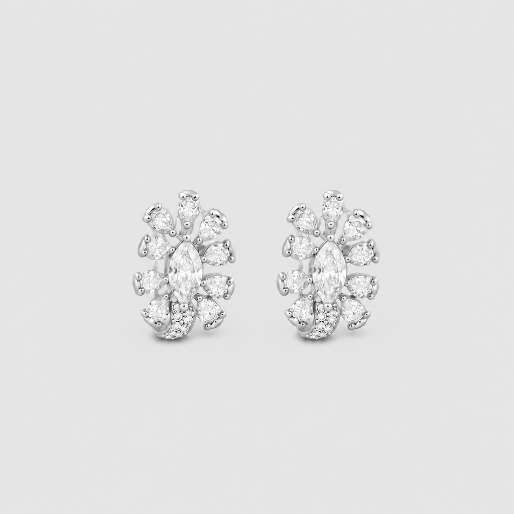A pair of silver-toned stud earrings featuring marquise-cut and round-cut clear gemstones arranged in a floral or snowflake-like cluster, set against a solid light gray background.