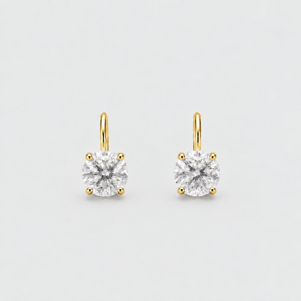 A pair of yellow gold stud earrings with round-cut clear gemstones in a four-prong setting, shown on a light gray background.