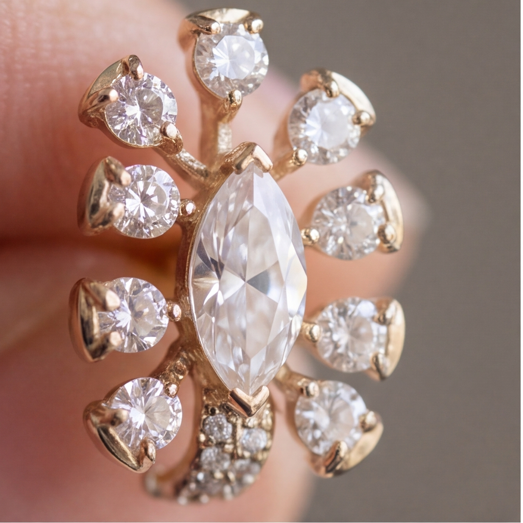 A close-up of a gold ring with a large marquise-cut clear center stone and eight surrounding round clear stones, shown being worn on a finger.