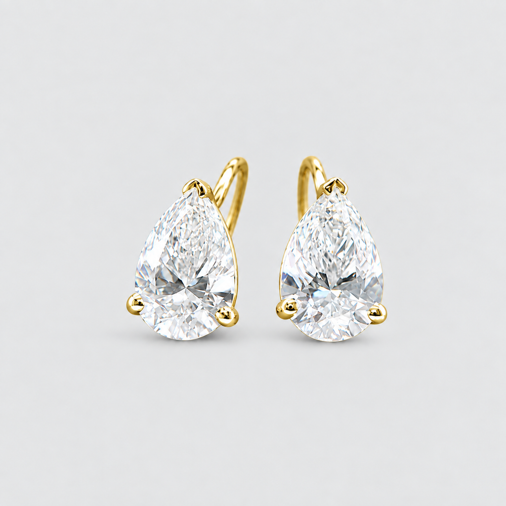 A pair of pear-cut diamond hoop earrings in yellow gold, shown on a light gray background.