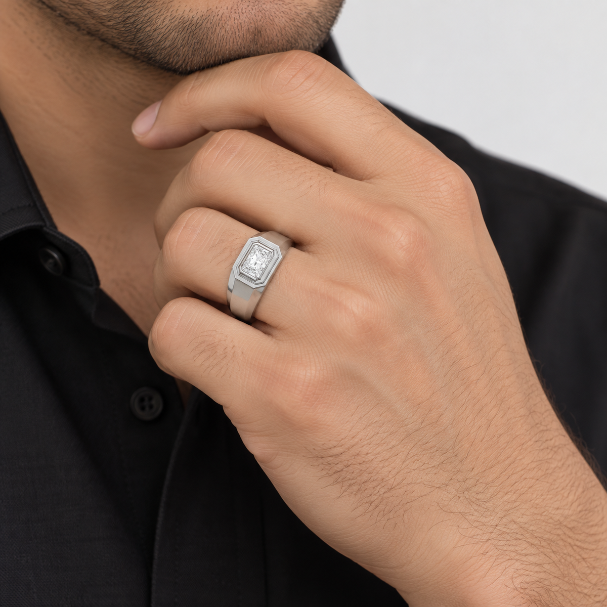 A silver-toned men's signet ring with a rectangular face and raised letter 'I' detail, shown worn on a man's ring finger.