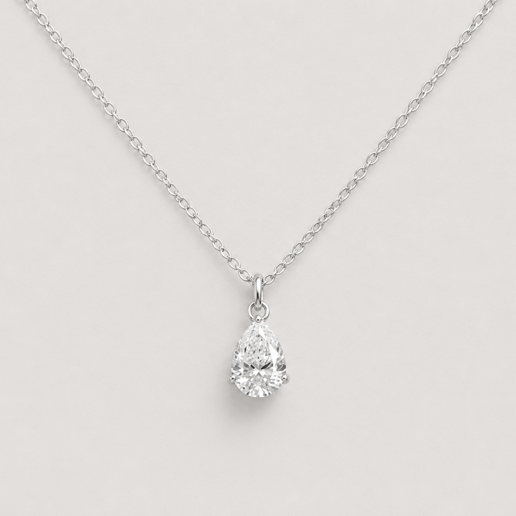 A silver chain necklace with a pear-cut clear gemstone pendant, displayed against a light gray background.