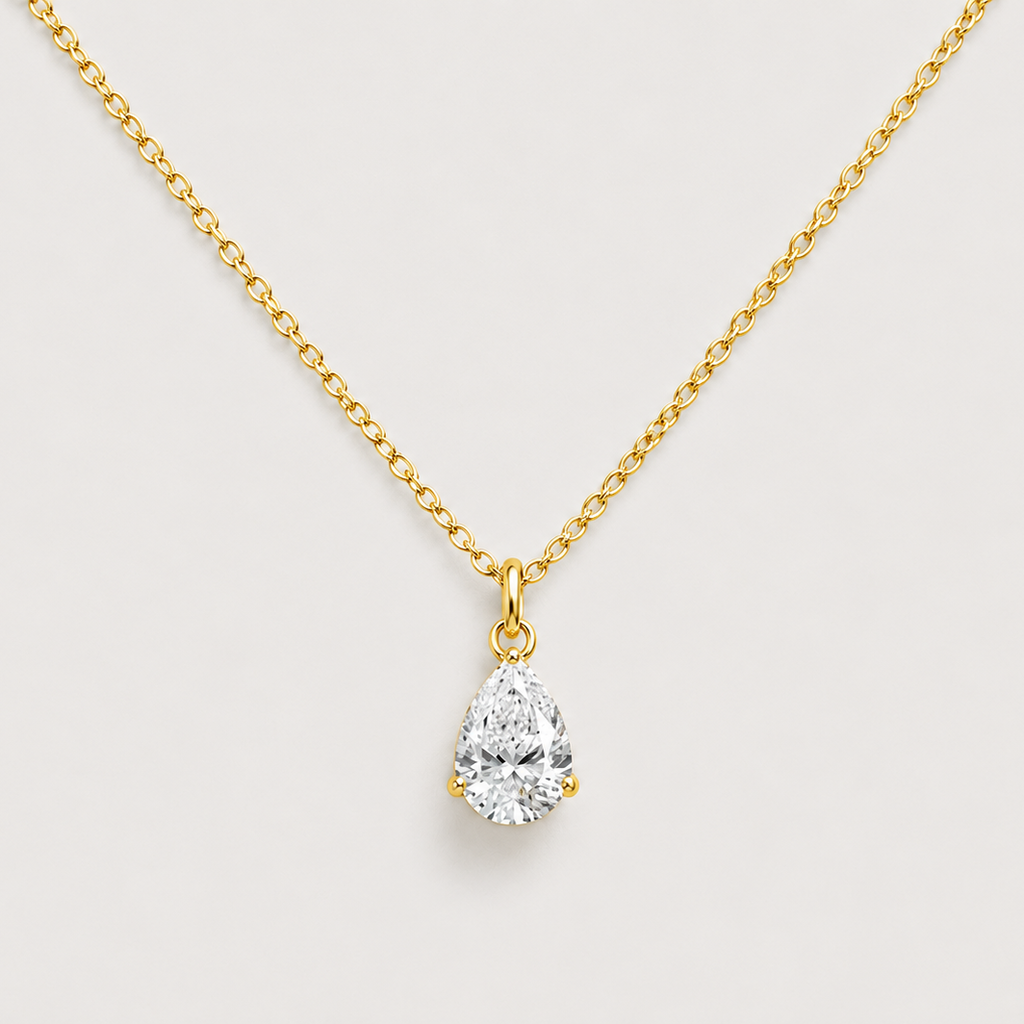 A gold chain necklace with a pear-cut diamond pendant, displayed against a light gray background.