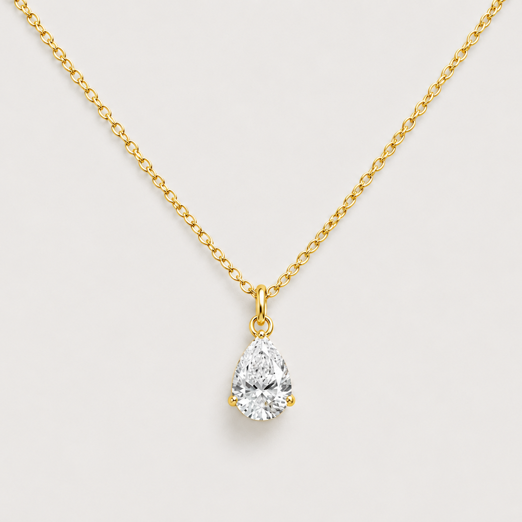 A gold chain necklace with a pear-cut diamond pendant, displayed against a light gray background.