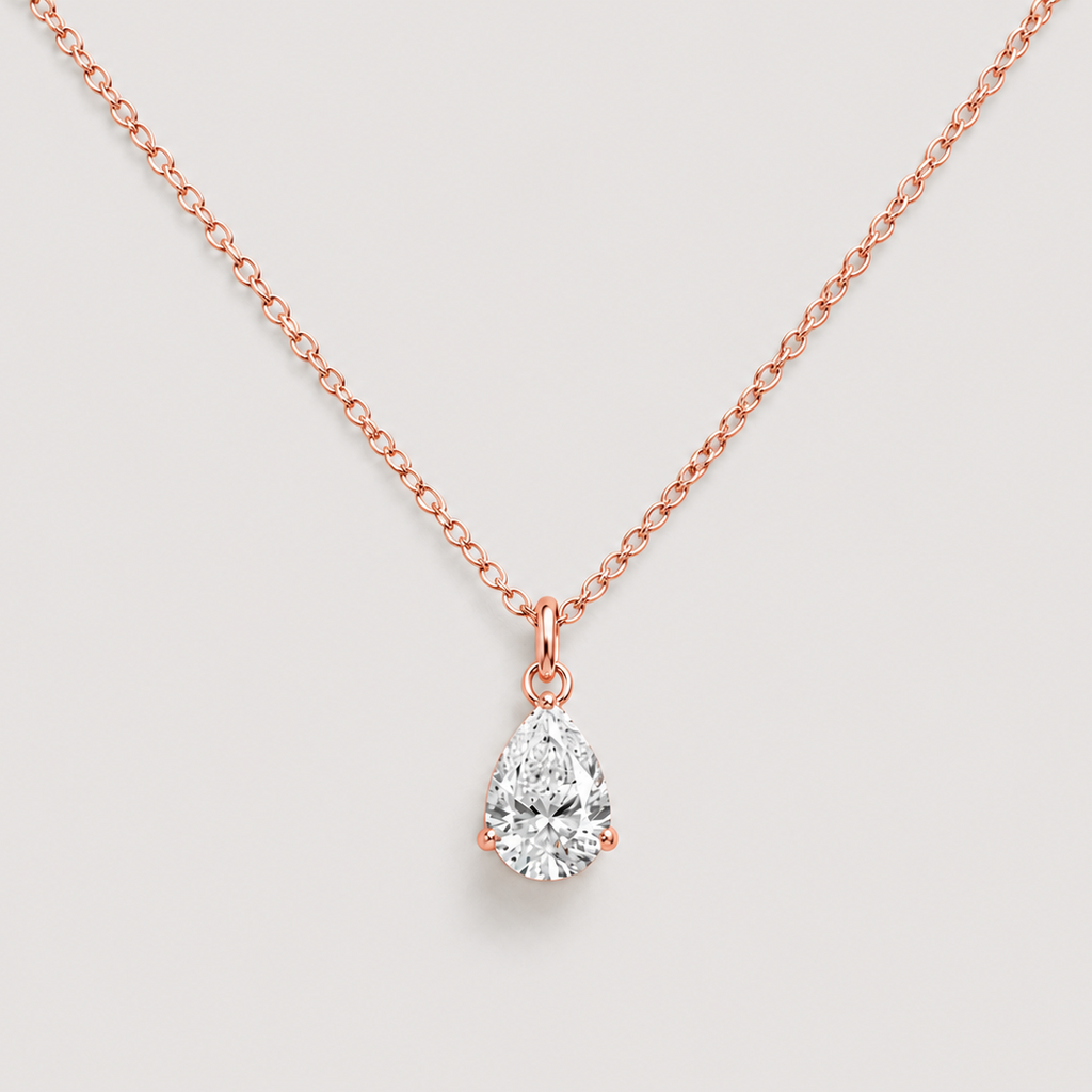 A rose gold necklace with a pear-cut diamond pendant, displayed against a light gray background.
