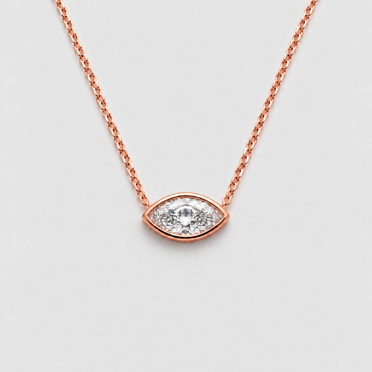 A rose gold eye-shaped pendant necklace with a clear central gemstone surrounded by small pavé-set stones, suspended on a delicate rose gold chain against a light gray background.