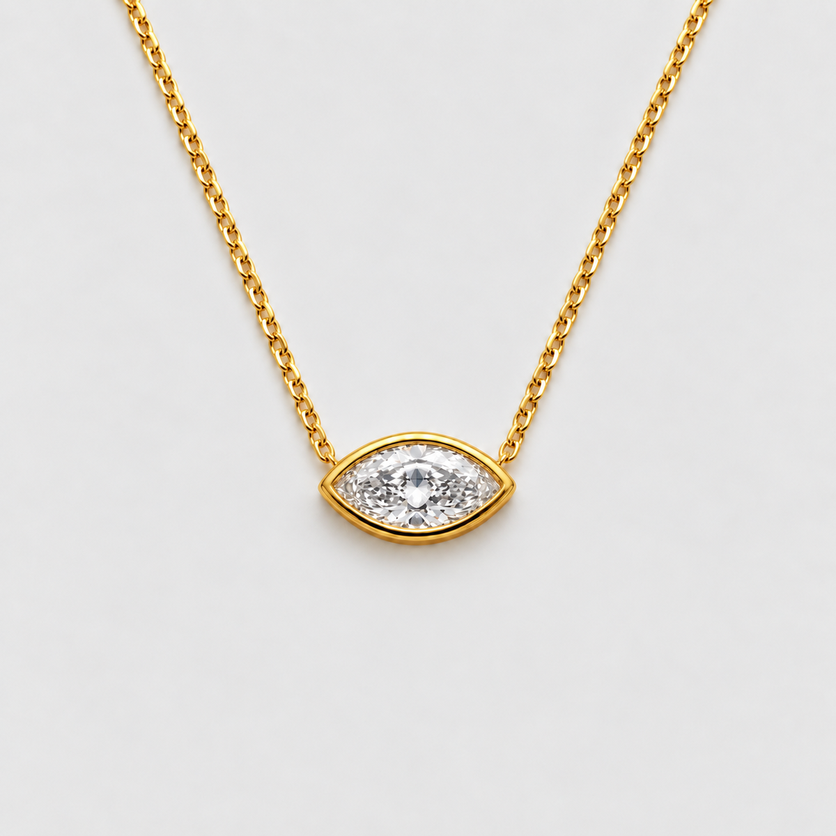 Gold chain necklace with an eye-shaped pendant featuring a clear central gemstone surrounded by small clear stones, shown on a light gray background.