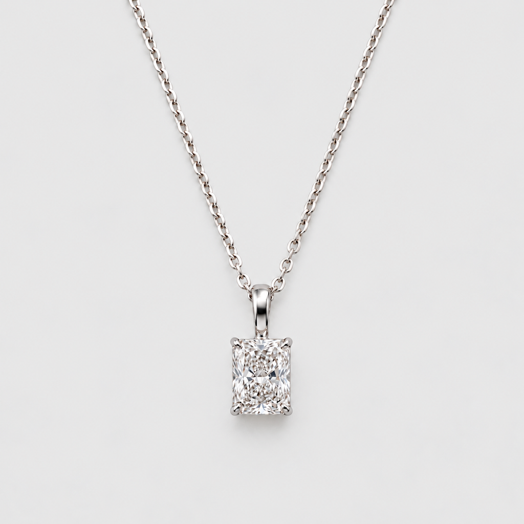A silver-toned necklace with a rectangular emerald-cut diamond pendant, displayed against a clean light gray background.