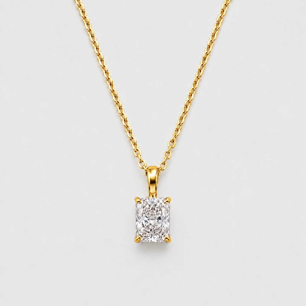 A yellow gold necklace with a rectangular emerald-cut diamond pendant, displayed against a clean light gray background.