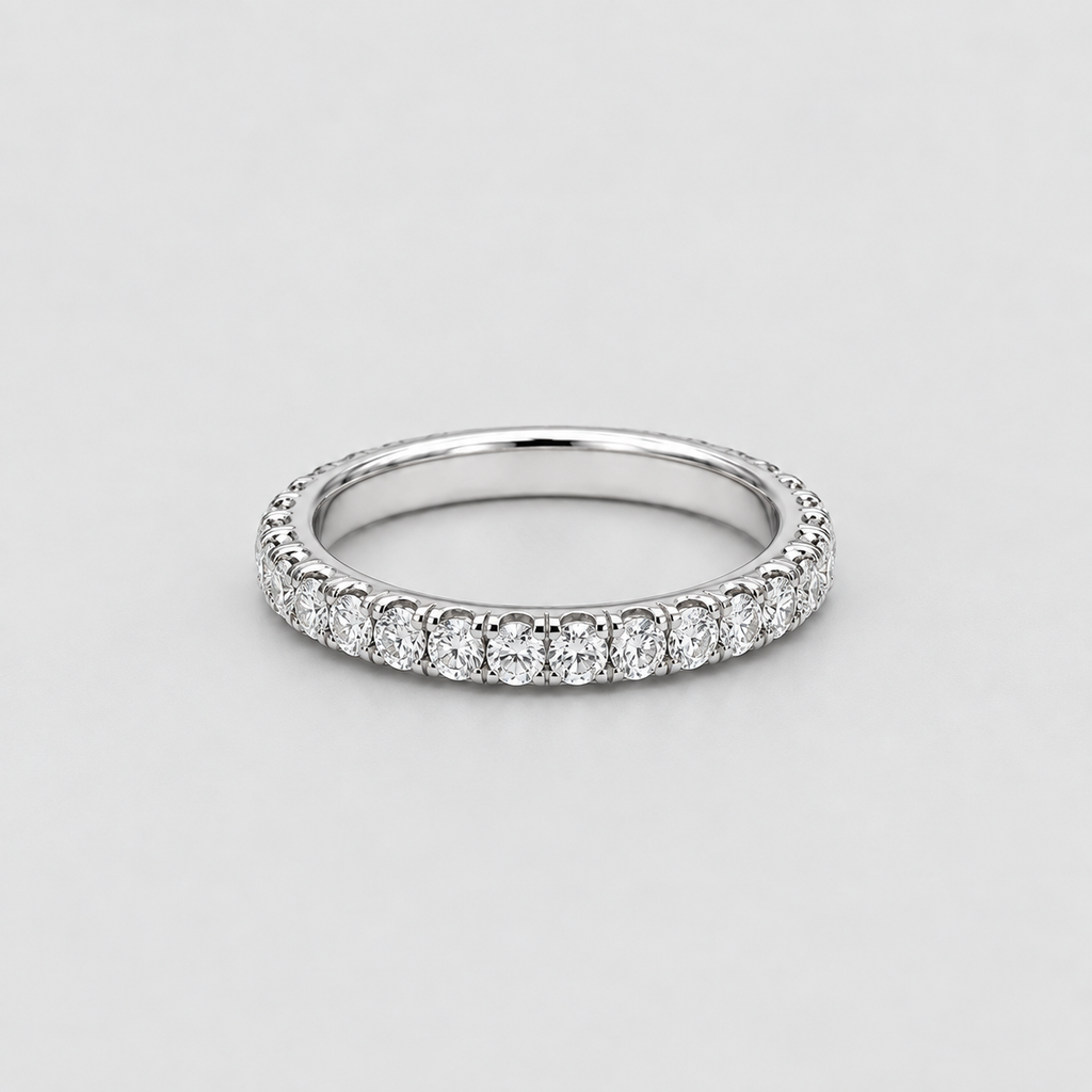 A silver-tone diamond eternity ring with a continuous row of round-cut diamonds set on a plain light gray background.
