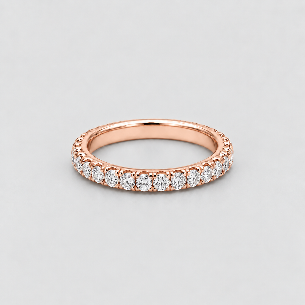 A rose gold eternity ring featuring a continuous row of round-cut clear gemstones, shown on a neutral light gray background.