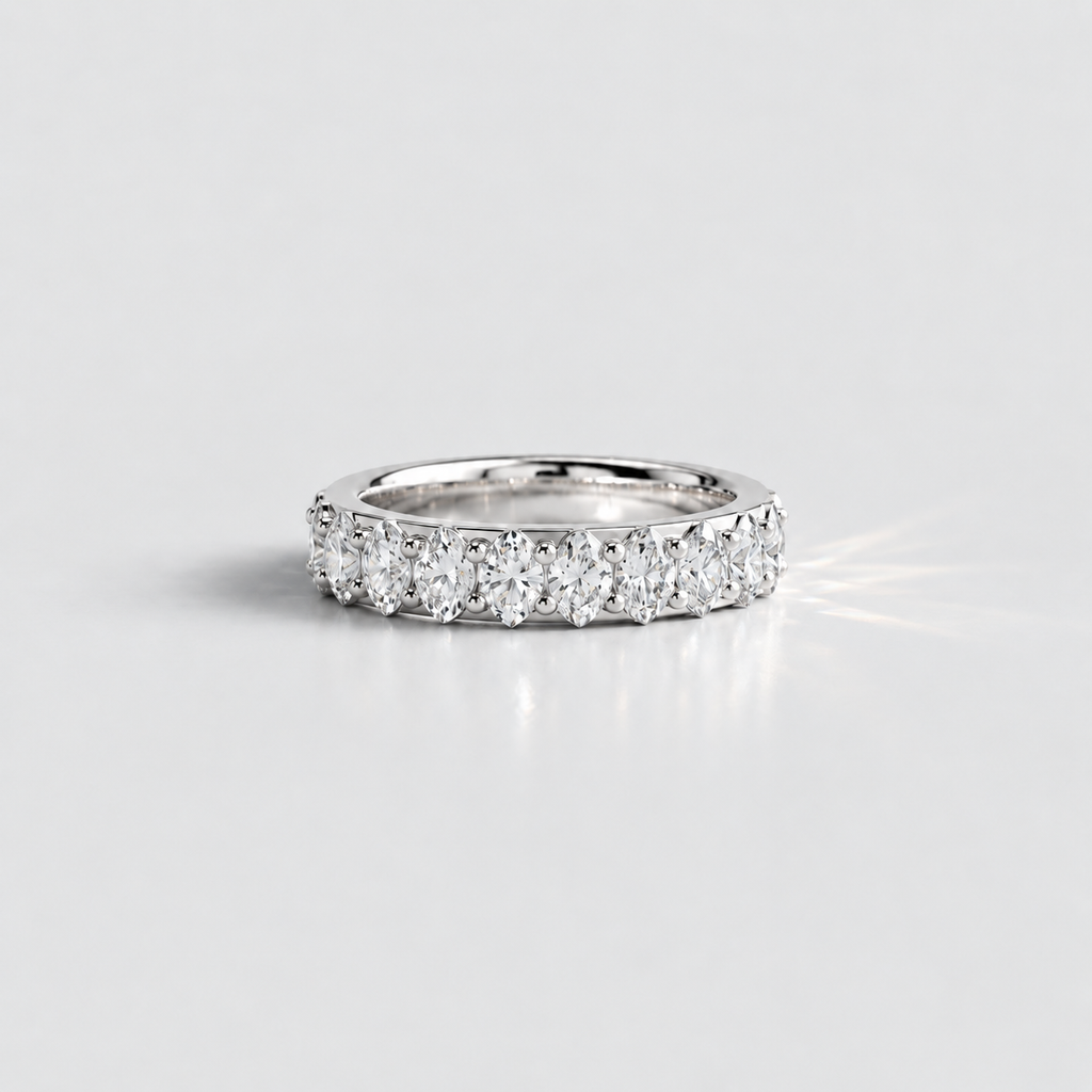 A silver diamond eternity ring with a row of round-cut diamonds set in a polished silver band, photographed on a clean light gray background.