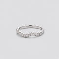 A silver wavy band ring with a row of clear pavé-set round diamonds, shown on a light gray background. The inner band is stamped with 'PT900 0.