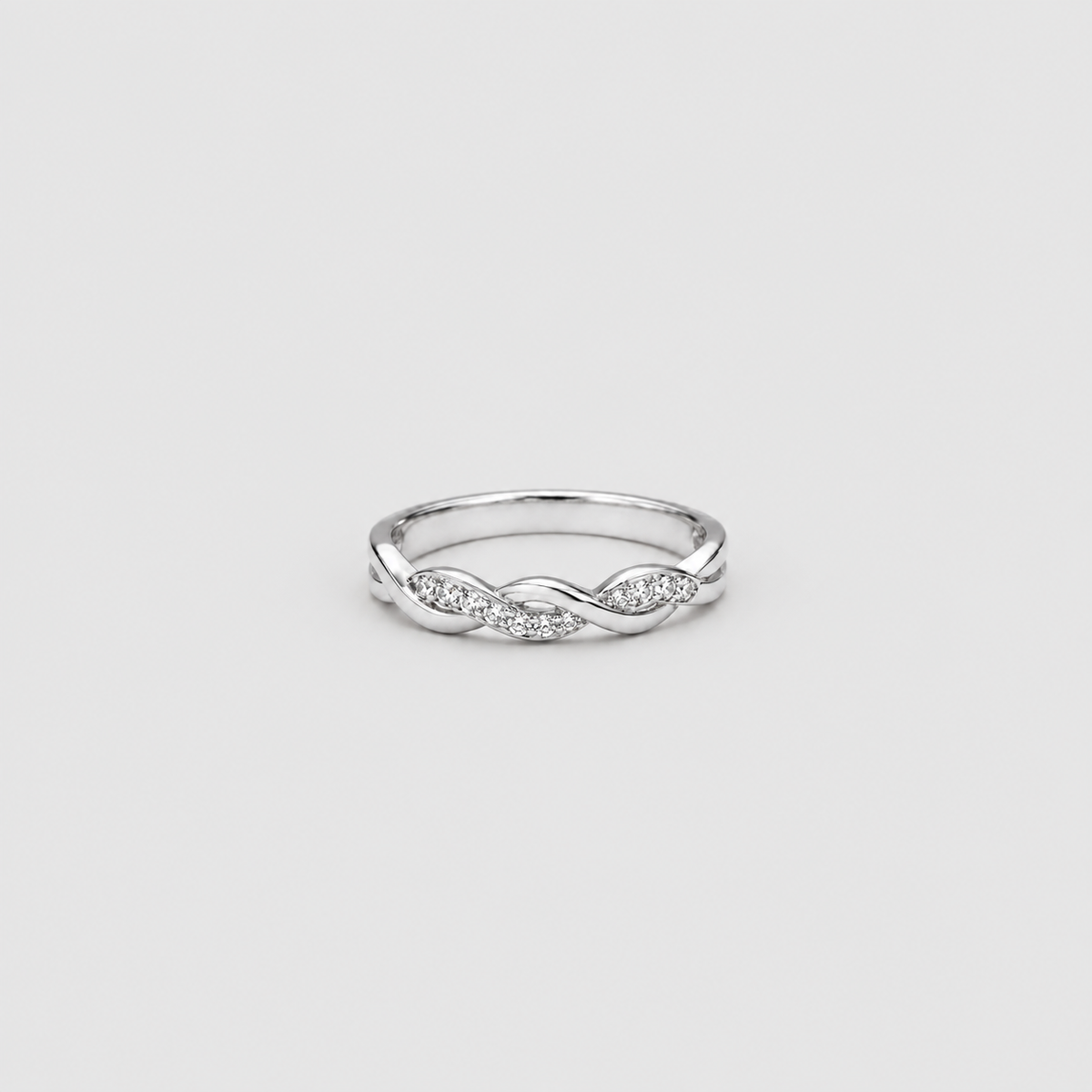 A silver-toned ring with a twisted infinity design accented by small clear pavé stones, centered on a light gray background.
