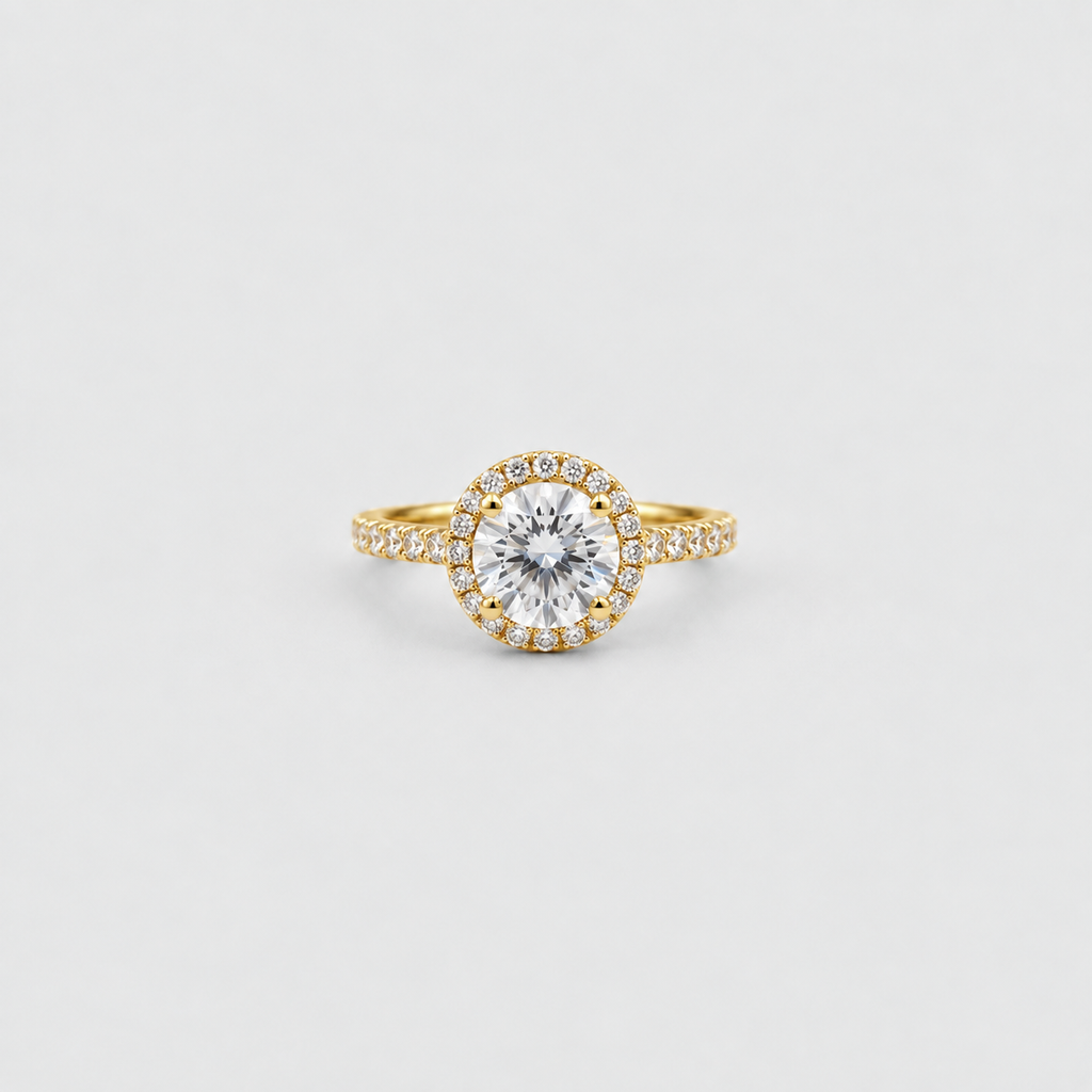 A yellow gold halo ring featuring a round brilliant-cut center stone surrounded by a halo of small pavé-set stones, with a matching pavé-set band, shown on a light gray background.
