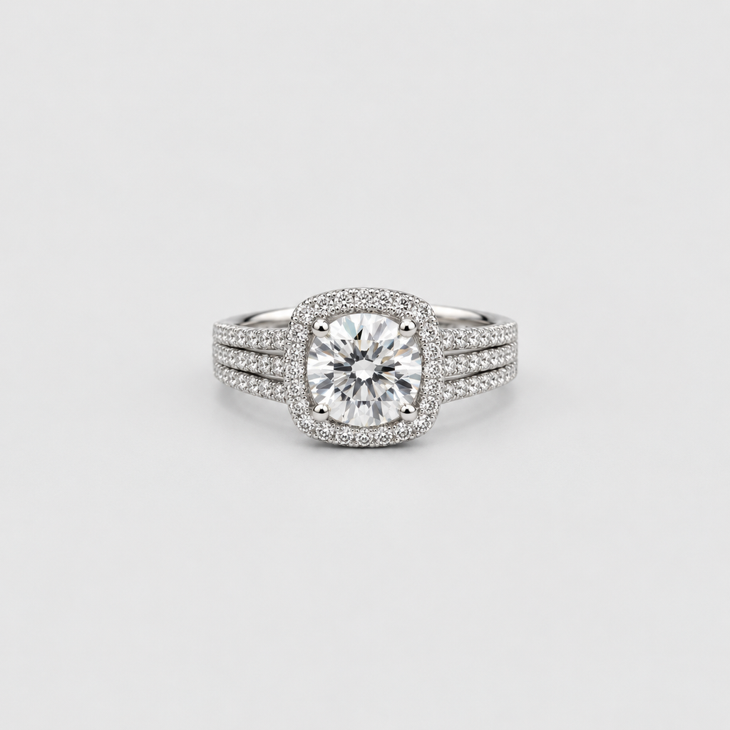 A silver-toned halo ring featuring a round brilliant-cut center stone surrounded by a halo of smaller stones, with a three-stone split band also paved with small diamonds, set against a light gray background.