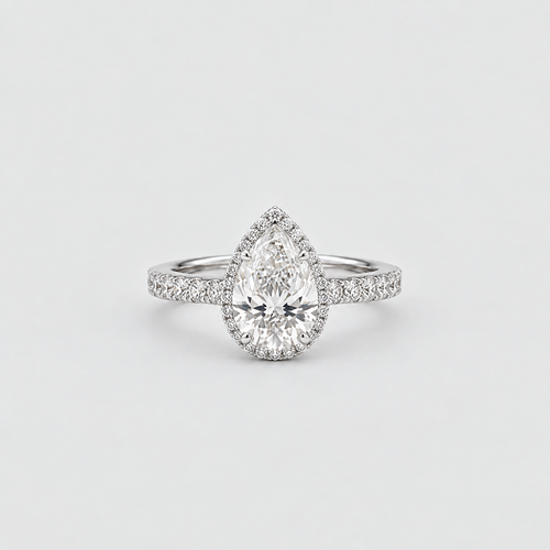 A pear-cut diamond halo ring in a silver-toned setting, featuring a halo of small diamonds around a larger pear-shaped center stone, with a diamond-accented band, photographed on a clean light gray background.
