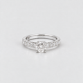 A silver solitaire engagement ring with a round-cut center stone and a pavé-set band, photographed on a clean light gray background.